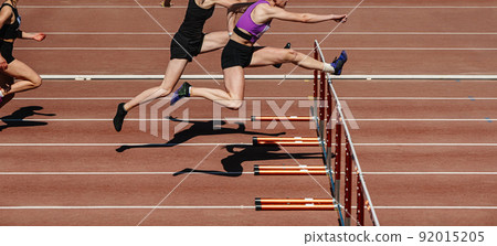 group female athletes run 100 meters with hurdles 92015205