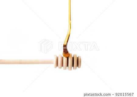 Tasty honey falling on a wooden dipper. Healthy food 92015567