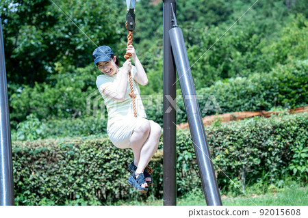 Active women playing with the Tarzan rope of the playset Active women playing with the Tarzan rope of the playset 92015608