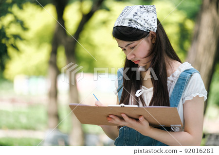 Young asian woman pianting and relaxing in park. Young asian woman pianting and relaxing in park. 92016281