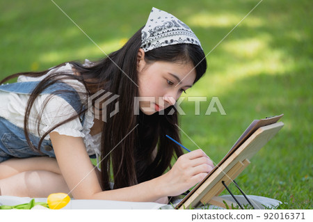Young asian woman pianting and relaxing in park. Young asian woman pianting and relaxing in park. 92016371