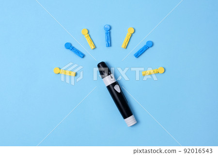 Diabetes concept on blue background. An abstract clock made of interchangeable needles and a lancet for blood sugar testing. Diabetes concept on blue background. An abstract clock made of interchangeable needles and a lancet for blood sugar testing. 92016543