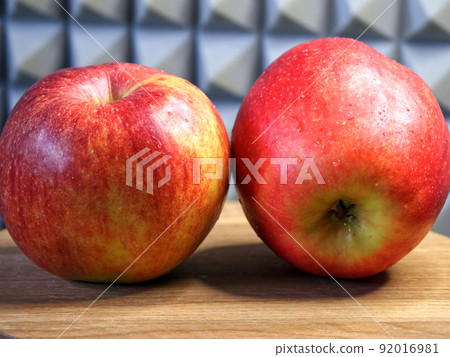 Two large red apples on a wooden surface. Ripe fruit close-up. Gala apples. Two large red apples on a wooden surface. Ripe fruit close-up. Gala apples. 92016981