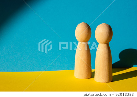 Two wooden mannequin on background of ukrainian flag. Creative concept symbol of died people or refugees. Copy space for your text. Yellow blue background 92018388