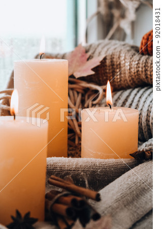 Hello Fall, celebrating autumn holidays at cozy home on the windowsill Hygge atmosphere Thanksgiving leaves, spices and candle on cozy knitted sweater in warm yellow lights. Raining Outside the window Hello Fall, celebrating autumn holidays at cozy home on the windowsill Hygge atmosphere Thanksgiving leaves, spices and candle on cozy knitted sweater in warm yellow lights. Raining Outside the window 92018431