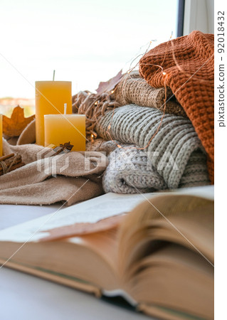 Book on first plan Thanksgiving and Hello Fall, celebrating autumn holidays at cozy home on the windowsill Hygge atmosphere Autumn leaves, spices and candle on cozy knitted sweater in warm yellow Book on first plan Thanksgiving and Hello Fall, celebrating autumn holidays at cozy home on the windowsill Hygge atmosphere Autumn leaves, spices and candle on cozy knitted sweater in warm yellow 92018432
