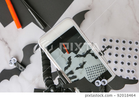 Taking photo on mobile phone of handmade Paper bats. Halloween holiday decorations. Happy Halloween party concept. Children's art project. DIY concept. Step by step 92018464