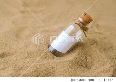 Letter in a bottle on the beach. Island lifestyle. Paper Message in a glass bottle with a cork on the sand. Note on salvation, please help. SOS concept. Copy space Letter in a bottle on the beach. Island lifestyle. Paper Message in a glass bottle with a cork on the sand. Note on salvation, please help. SOS concept. Copy space 92018552