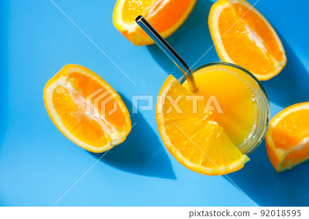 Glass of fresh squeezing Orange juice with eco metal drinking straw sliced fruits on blue background. Fruit juice, fresh cold. Refreshment in summer. Clean eating, weight loss, healthy dieting Glass of fresh squeezing Orange juice with eco metal drinking straw sliced fruits on blue background. Fruit juice, fresh cold. Refreshment in summer. Clean eating, weight loss, healthy dieting 92018595