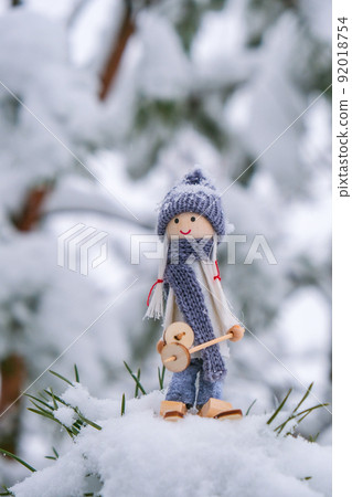 Angel gnome in scarf and knitted hat skiing on snowy fir branch Elf toy on skis in snowy landscape Copy space for text. New year and Merry christmas greeting card background. Ski winter resort 92018754