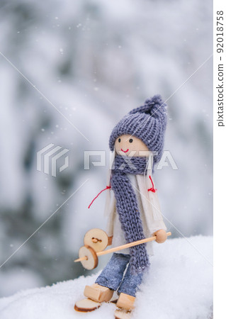 Angel gnome in scarf and knitted hat skiing on snowy fir branch Elf toy on skis in snowy landscape Copy space for text. New year and Merry christmas greeting card background. Ski winter resort 92018758