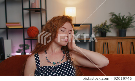 Displeased redhead woman rubbing temples to cure headache problem, suffering from migraine, stress 92019746