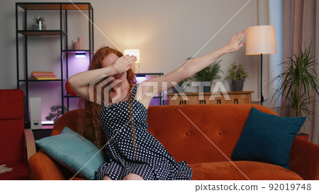 Trendy cheerful positive cute girl dancing, moving to rhythm making dub dance gesture at modern home Trendy cheerful positive cute girl dancing, moving to rhythm making dub dance gesture at modern home 92019748