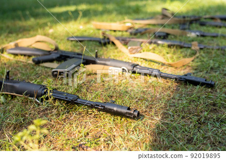 Kalashnikov assault rifles lying on the ground. Weapon in the grass. 92019895