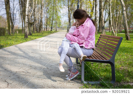 A daughter cuddles with her mother. Time together in the spring in the city park. A daughter cuddles with her mother. Time together in the spring in the city park. 92019921