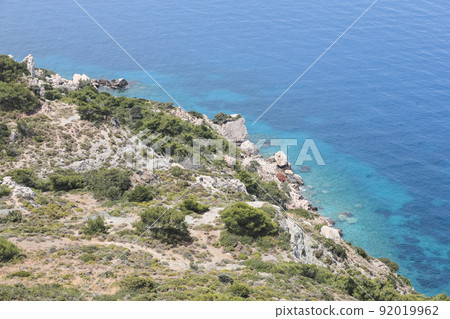Beautiful seascape with green grass, blue sky and sea or ocean. Nature landscape for banner, wallpaper or postcard. mountainous terrain in the haze. 92019962