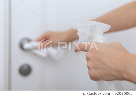Cleaning white door handles with an antiseptic wet wipe and sanitizer spray. Disinfection in hospital and public spaces against corona virus. Woman hand using towel for cleaning home room door link. Cleaning white door handles with an antiseptic wet wipe and sanitizer spray. Disinfection in hospital and public spaces against corona virus. Woman hand using towel for cleaning home room door link. 92020003