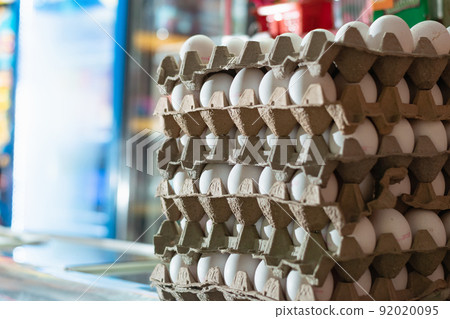 view of several white hen's eggs in a glass display case. sale of eggs in a grocery store. eggs rich in albumen protein ready to be sold and consumed in different foods. poultry and food concept. 92020095