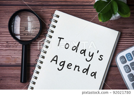 Today's agenda text on notepad. Magnifying glass and calculator background. Today's agenda text on notepad. Magnifying glass and calculator background. 92021780