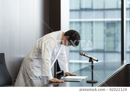 Male doctor in white coat giving an apology press conference Male doctor in white coat giving an apology press conference 92022129