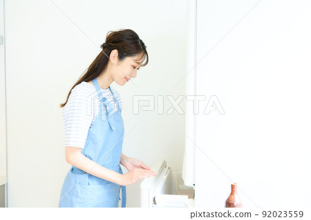 A woman who opens a refrigerator 92023559