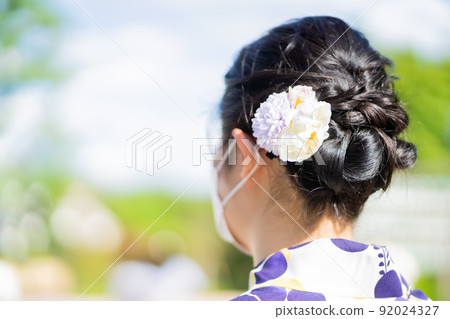 Back view of a woman dressed in fresh green and wearing a hairstyle 92024327