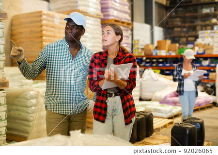 Woman and man discussing work details in storehouse 92026065