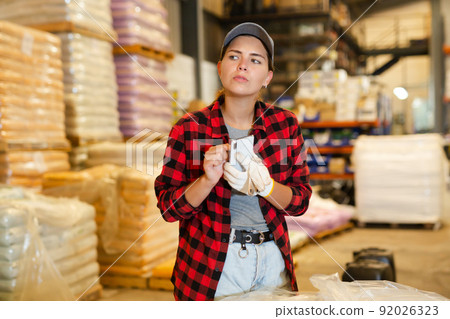 Female warehouse worker using smartphone to check quantity of goods 92026323