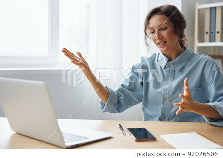 Furious angry evil beautiful curly businesswoman hates computer crash having problem with broken laptop swings at gadget raises hands up sitting at home office. Freelancer work concept. Copy space 92026506