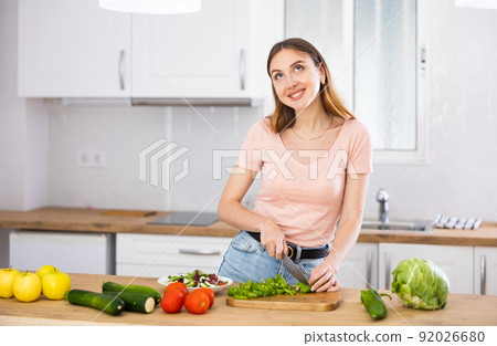 Portrait of positive woman cooking salad at home Portrait of positive woman cooking salad at home 92026680