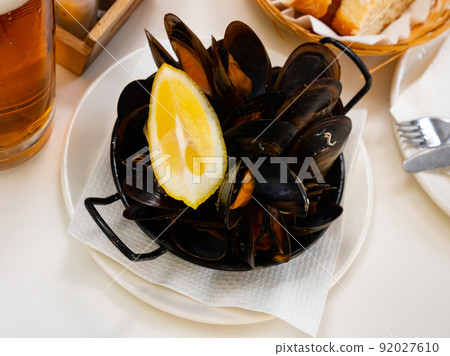 Steamed mussels with lemon wedge in metal serving pan Steamed mussels with lemon wedge in metal serving pan 92027610