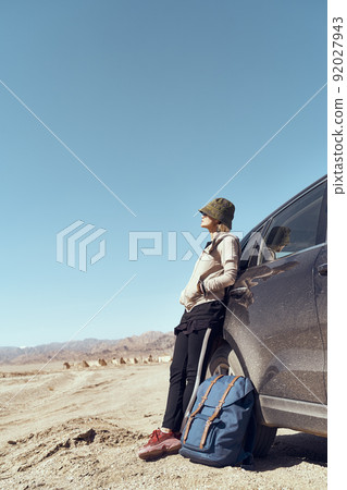 asian woman traveler leaning against car looking at view in gobi desert 92027943