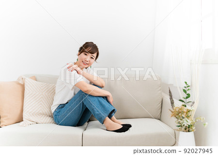 (Looking at the camera) A Japanese woman in jeans sitting on the sofa at home and relaxing 92027945