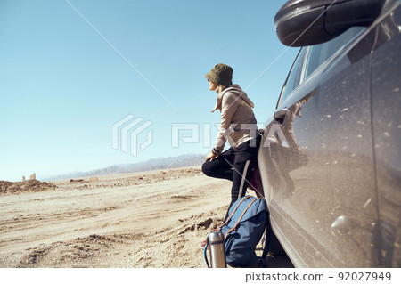 asian woman traveler leaning against car looking at view in gobi desert 92027949
