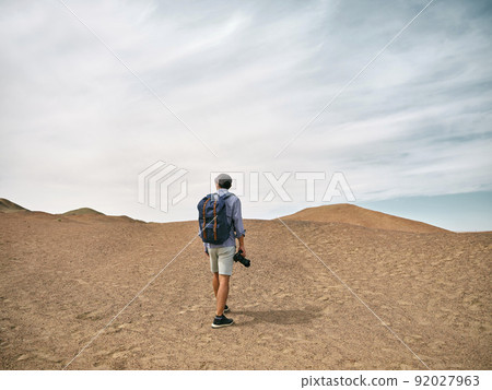 asian male backpacker landscape photographer walking on a hill looking at view, rear view 92027963