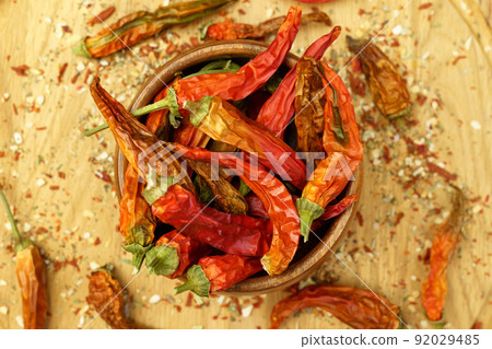 Chili peppers falling, spice seasoning, dried red peppers on a wooden table, background, dry paprika. Selective focus Chili peppers falling, spice seasoning, dried red peppers on a wooden table, background, dry paprika. Selective focus 92029485