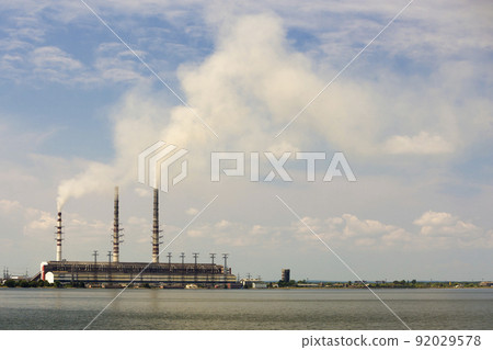Thermal power station tall pipes with thick smoke reflected in lke water surface. Pollution of environment concept. Thermal power station tall pipes with thick smoke reflected in lke water surface. Pollution of environment concept. 92029578
