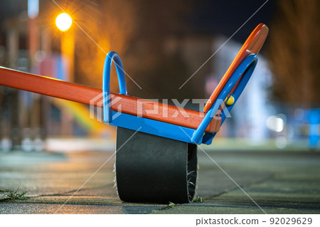 Seesaw swing in preschool yard with soft rubber flooring at night. 92029629