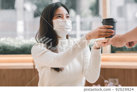 Woman wearing mask and pick up coffee served by a waiter Woman wearing mask and pick up coffee served by a waiter 92029924