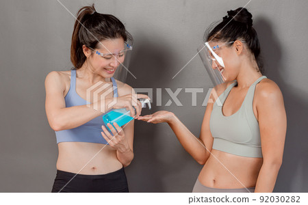 Asian young women wearing face shield and washing their hands in gym Asian young women wearing face shield and washing their hands in gym 92030282
