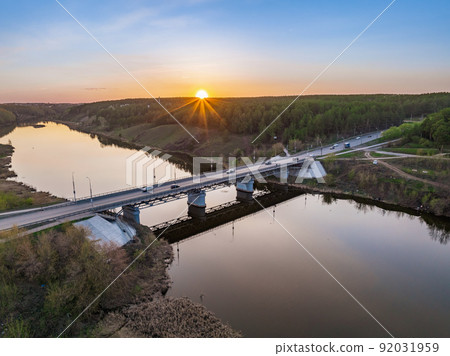 Beautiful view of the bridge across the Iset river in the city of Kamensk-Uralsky at sunset in spring. Kamensk-Uralskiy, Sverdlovsk region, Ural mountains, Russia. 92031959