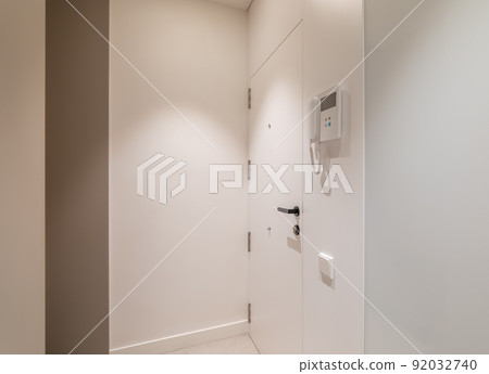 Entrance hall area in modern refurbished apartment. White walls and door with intercom system. Entrance hall area in modern refurbished apartment. White walls and door with intercom system. 92032740