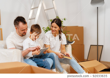 Portrait of happy family with cardboard boxes in new house at moving day Portrait of happy family with cardboard boxes in new house at moving day 92033635