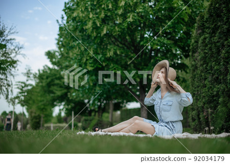 Romantic girl with hat on picnic in park Romantic girl with hat on picnic in park 92034179