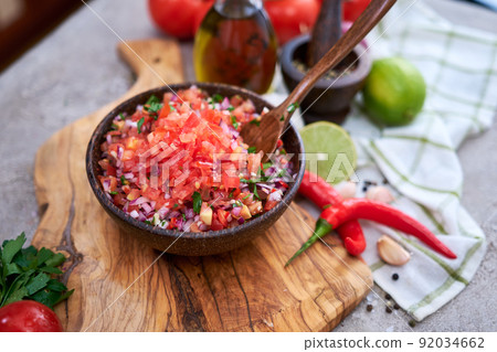 making salsa dip sauce - chopped garlic, tomatoes and onion in wooden bowl making salsa dip sauce - chopped garlic, tomatoes and onion in wooden bowl 92034662