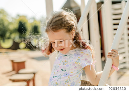 A charming girl is having fun on a swing on a summer day. Childhood, recreation, summer time A charming girl is having fun on a swing on a summer day. Childhood, recreation, summer time 92034810