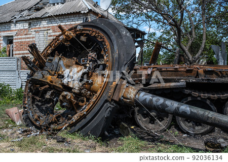 A burnt Russian tank near a residential building. War in Ukraine 2022. Russian missiles in Kharkiv countryside Ukraine. Russian aggression. Russian attack on Ukraine. 92036134