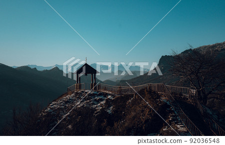 Gazebo with a bell on the background of mountains near the church Gazebo with a bell on the background of mountains near the church 92036548