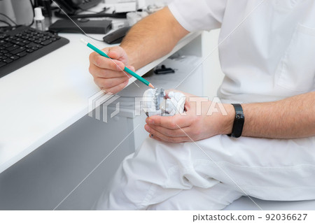 hands of a dentist close-up. dentist with a pencil shows jaw defects on a plaster cast. hands of a dentist close-up. dentist with a pencil shows jaw defects on a plaster cast. 92036627