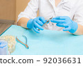 Orthodontic treatment. Alignment of the dentition or bite. Unrecognizable person. Hands in protective gloves close-up with a tool. 92036631